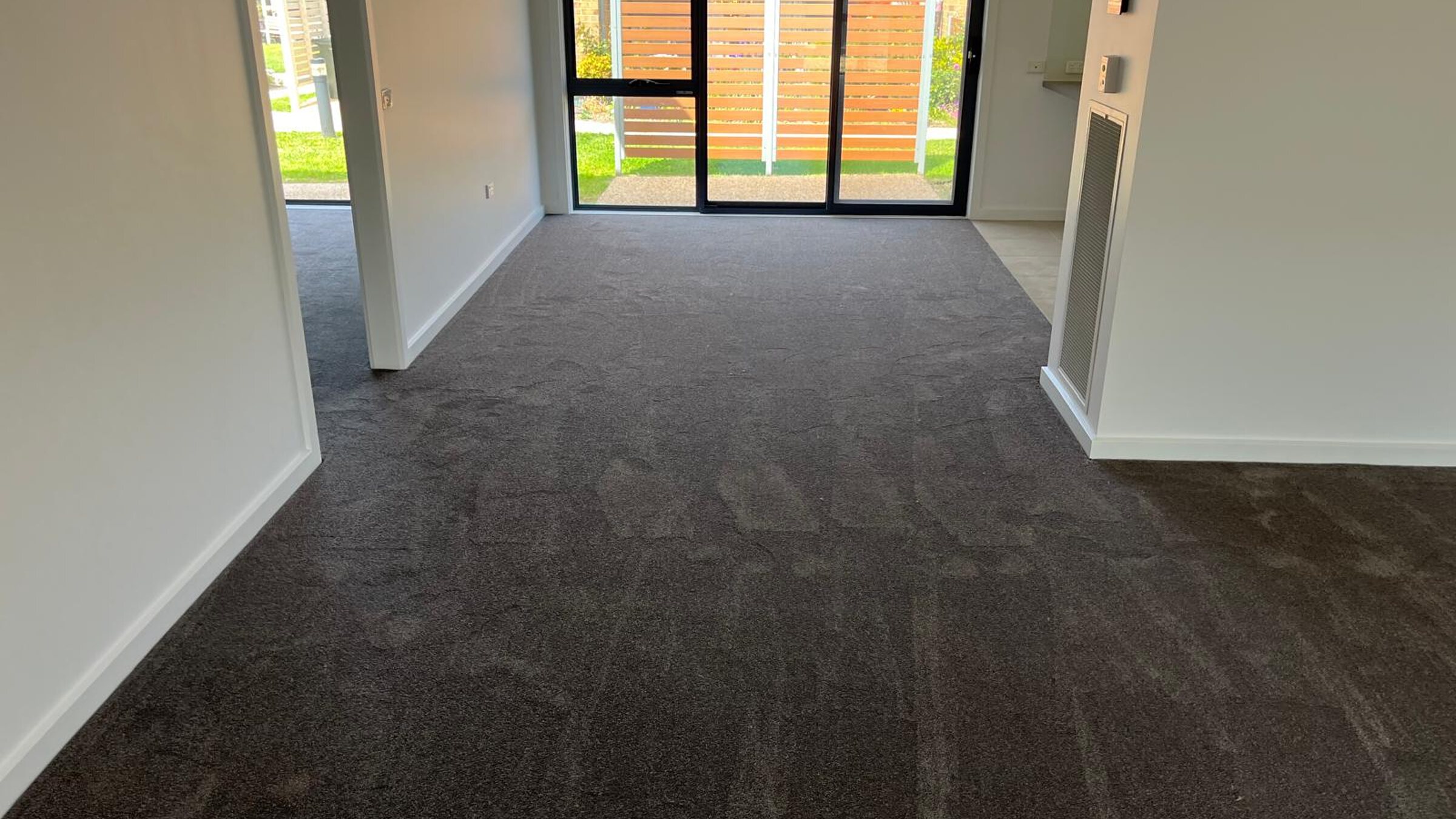 New charcoal carpet installed in a living room with sliding doors to the garden