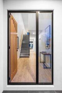 Timber flooring visible through glass doors into a hallway and staircase