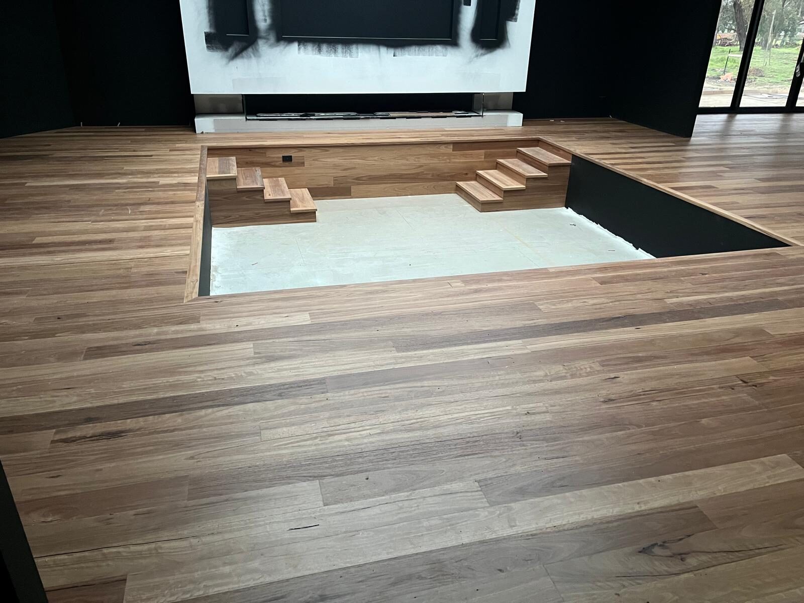 Timber flooring installation in progress around a sunken lounge