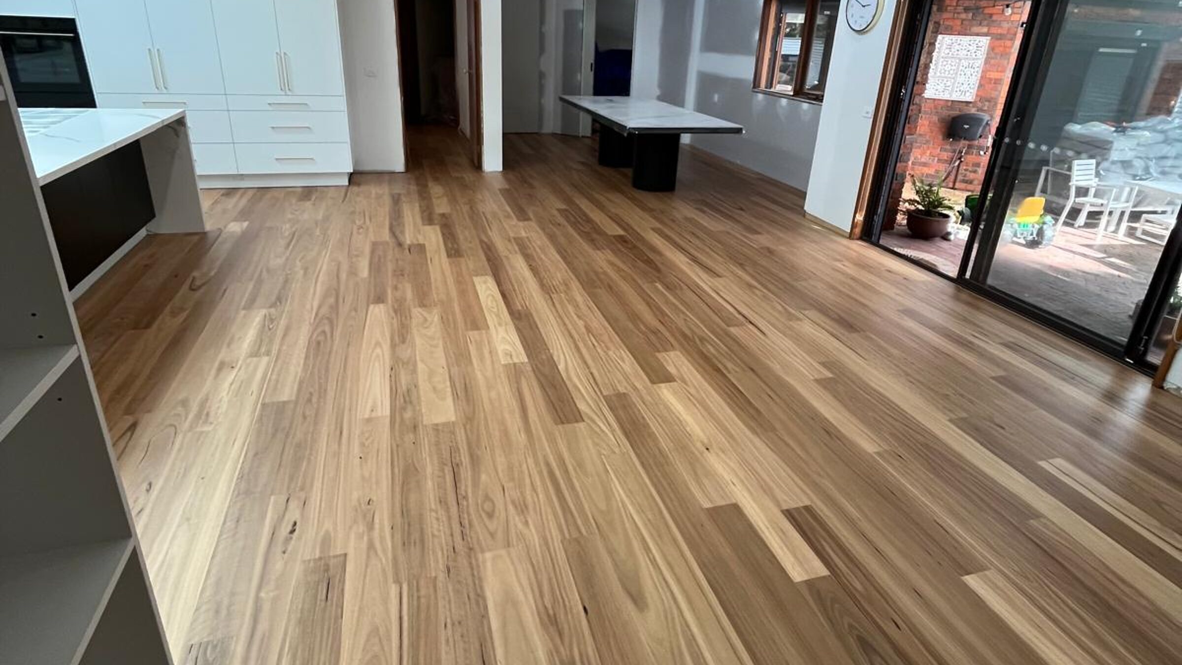 Timber flooring through a large open plan living area with raked ceilings